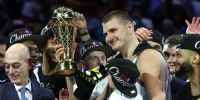 NIKOLA JOKIC levanta con una mano a su hijo y con la otra el trofeo de MVP de la NBA. 